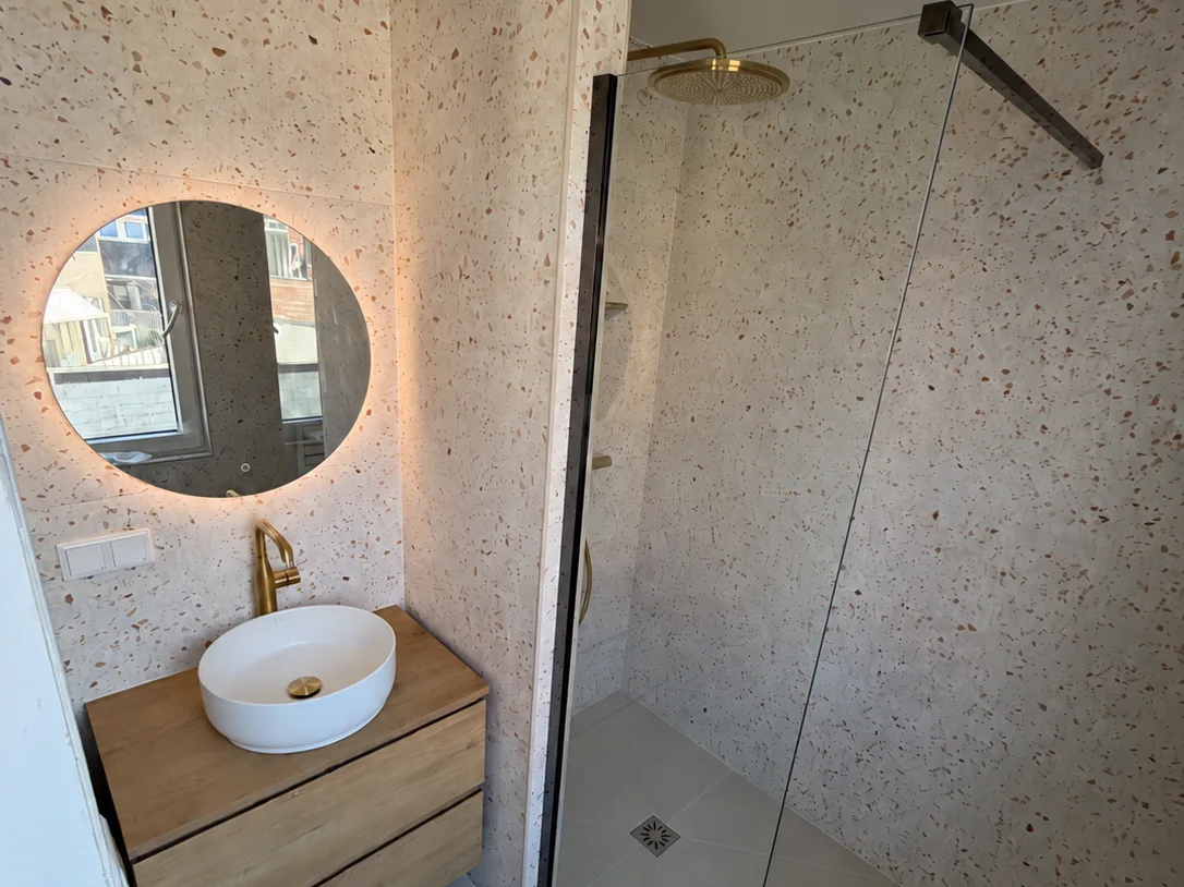 Badkamer met een terrazzowand die zonder zichtbaar profiel om de hoek loopt, opgeleverd door Clootcrans in Rotterdam