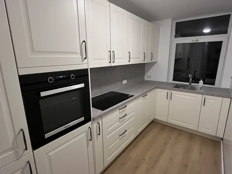 Opgeleverde keuken in hoekopstelling met een inbouwoven en een houten vloer