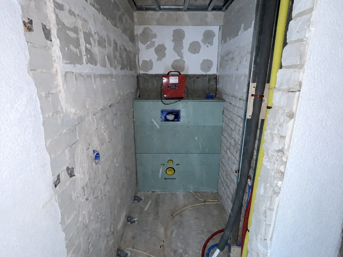 Het toilet tijdens de opbouw, met het leidingwerk en het inbouwreservoir in het zicht
