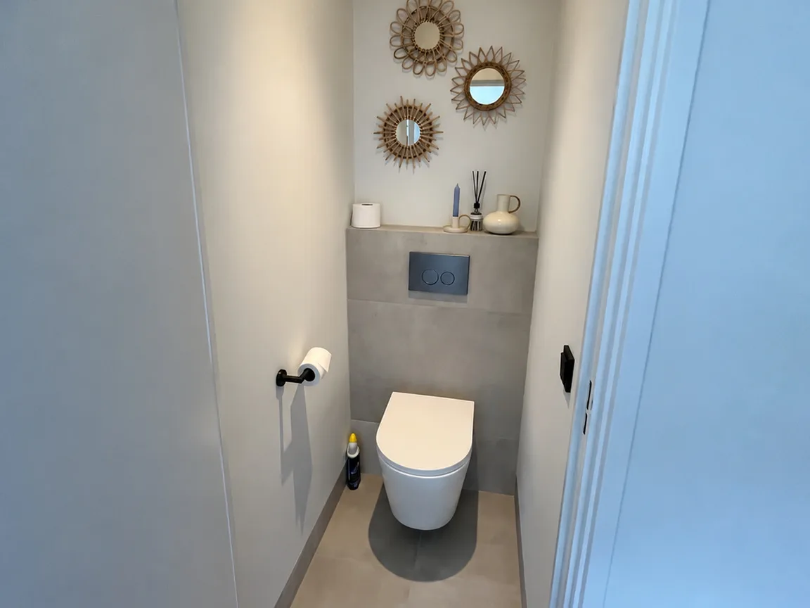 Hetzelfde toilet na de renovatie, met een zwevend closet en een nieuwe wandafwerking
