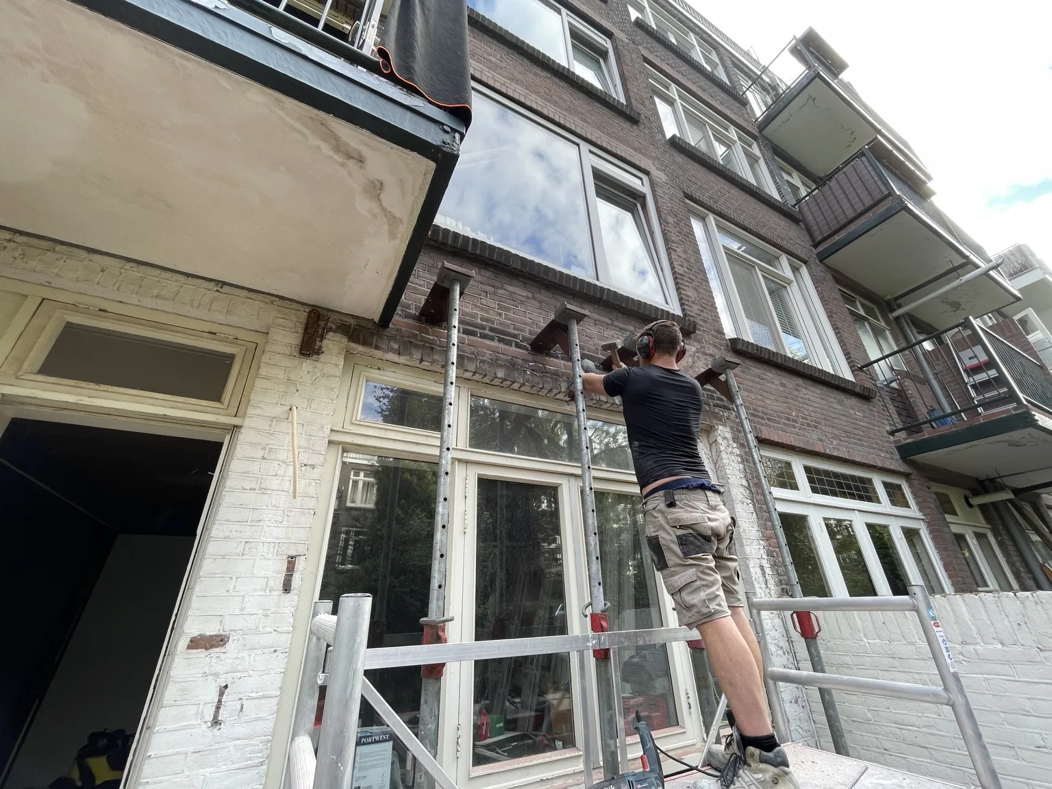 Een vakman van Clootcrans plaatst stempels onder een gevelopening tijdens constructiewerk in Rotterdam